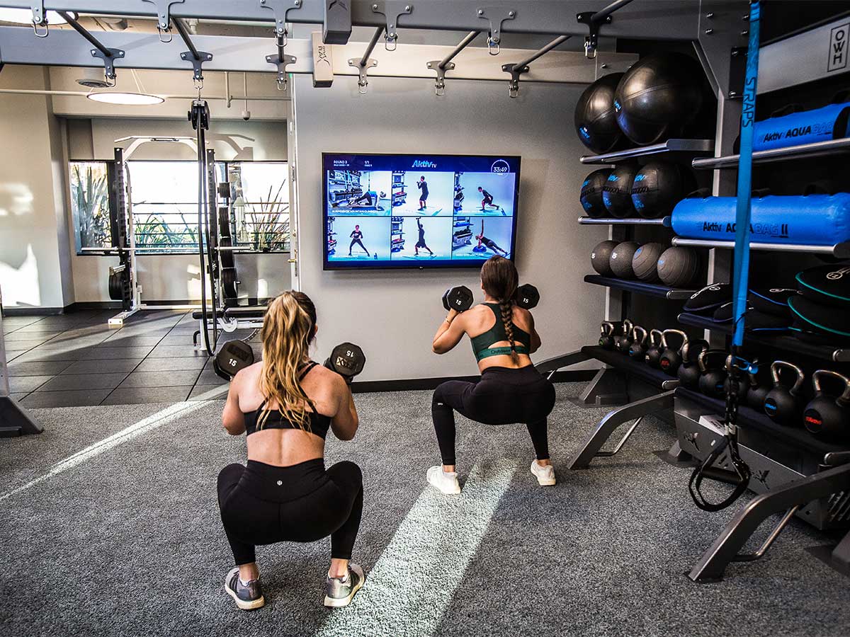 aktiv-gym-tv-digital-fitness-health-club Two girls working out with AktivTV exercise guidance.